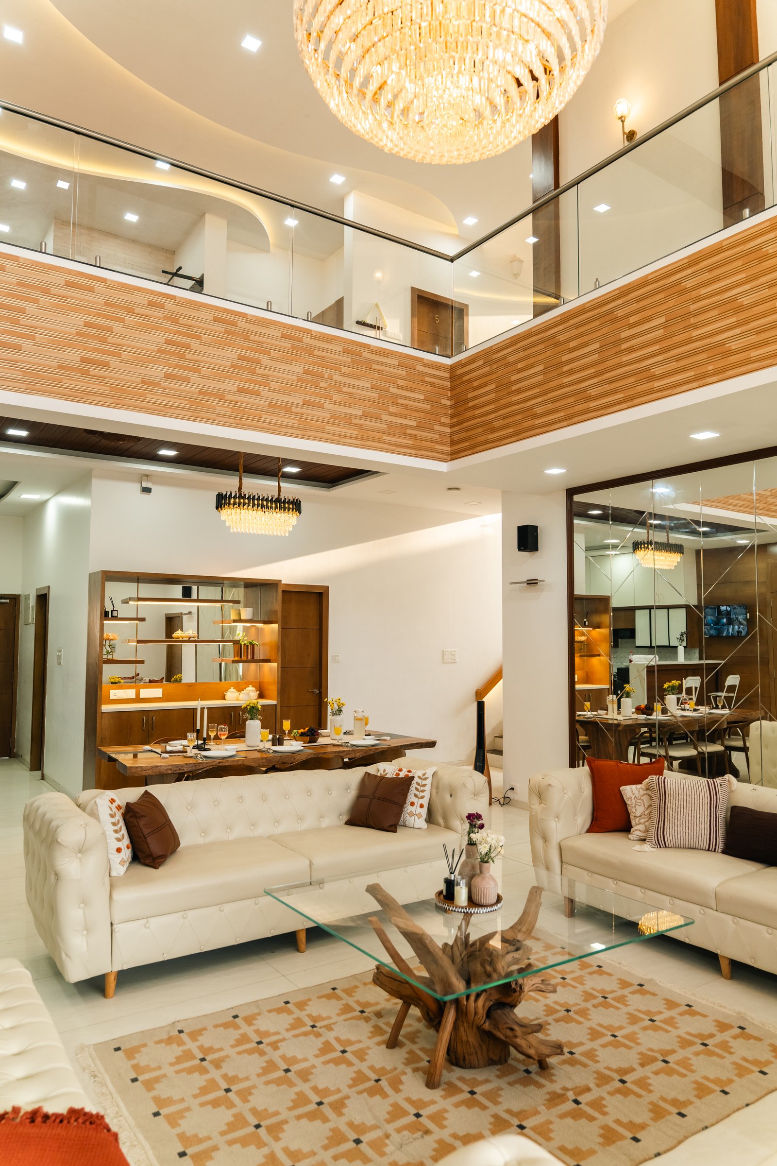 DOUBLE-HEIGHT LIVING – 16-foot crystal chandelier centred, full-height glass behind, hills visible.